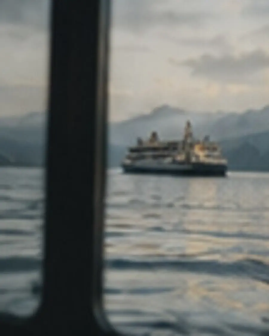 A ferry passing on open water, seen through a window